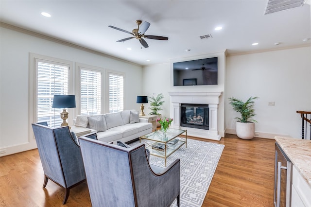 living room with crown molding, a fireplace, and light wood-type flooring