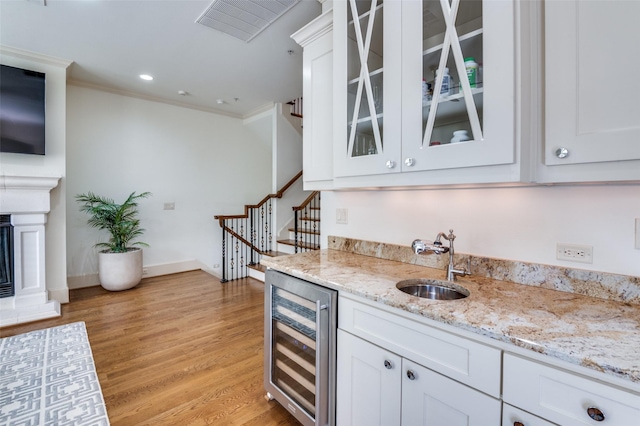 bar featuring white cabinetry, sink, wine cooler, and light stone counters