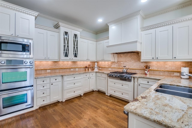 kitchen with dark wood-type flooring, stainless steel appliances, light stone countertops, and white cabinets