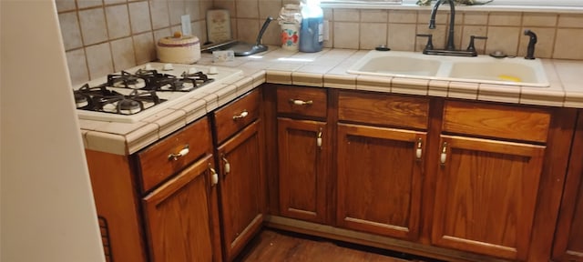 kitchen with sink, tile countertops, backsplash, and white gas cooktop