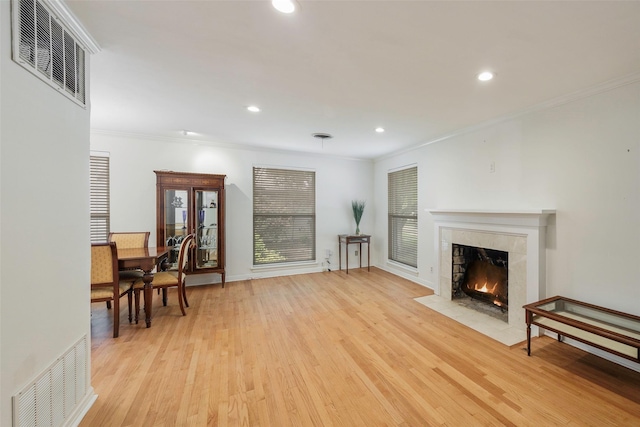 living room featuring crown molding, a fireplace, and light wood-type flooring