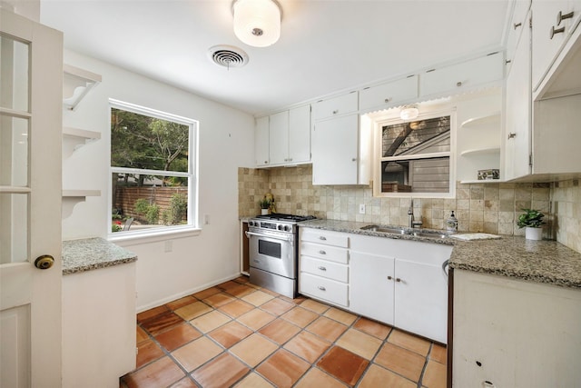 kitchen featuring light stone countertops, sink, white cabinets, and high end range