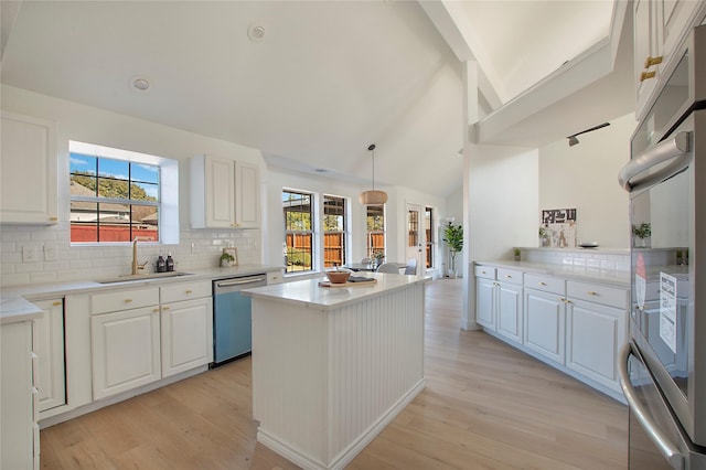 kitchen with stainless steel appliances, white cabinetry, sink, and decorative light fixtures