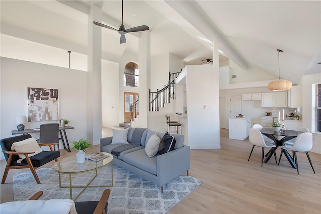 living room with beamed ceiling, ceiling fan, high vaulted ceiling, and light hardwood / wood-style flooring