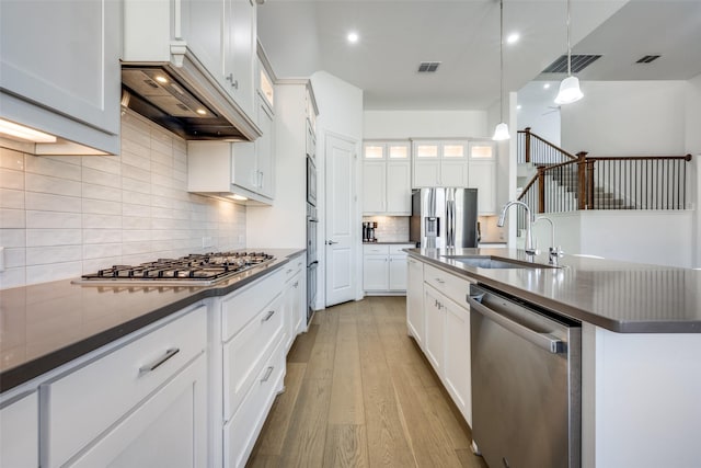 kitchen featuring sink, white cabinetry, light hardwood / wood-style flooring, appliances with stainless steel finishes, and pendant lighting