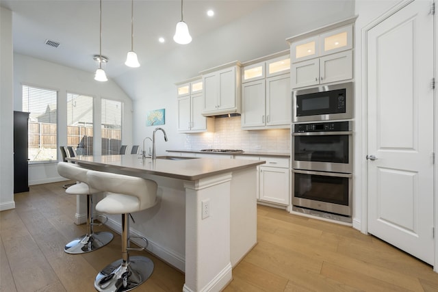 kitchen with white cabinetry, an island with sink, sink, and hanging light fixtures