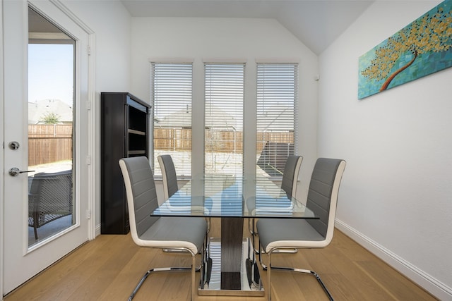 dining area with a healthy amount of sunlight, lofted ceiling, and light wood-type flooring