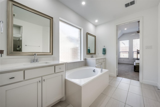 bathroom with tile patterned flooring, vanity, ceiling fan, and a tub to relax in