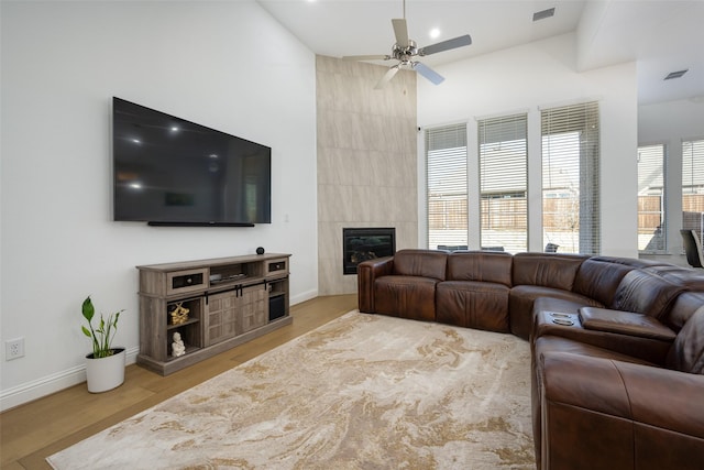 living room with a tile fireplace, hardwood / wood-style floors, and ceiling fan