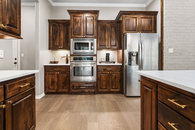 kitchen with appliances with stainless steel finishes, decorative backsplash, crown molding, dark brown cabinets, and light wood-type flooring