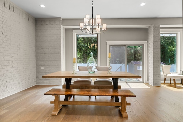 dining area with brick wall, breakfast area, a notable chandelier, and light hardwood / wood-style flooring