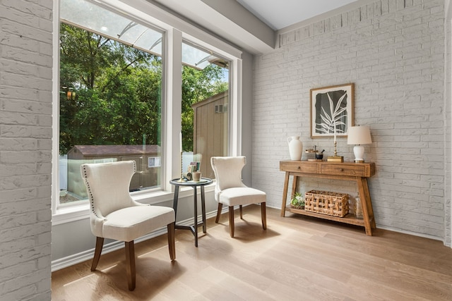 sitting room with hardwood / wood-style floors and brick wall