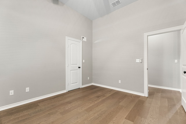 empty room featuring hardwood / wood-style flooring and a towering ceiling