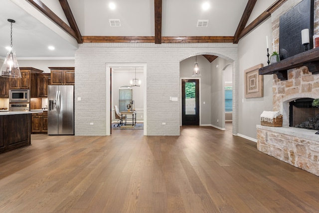 living room featuring lofted ceiling with beams, brick wall, hardwood / wood-style flooring, and a fireplace