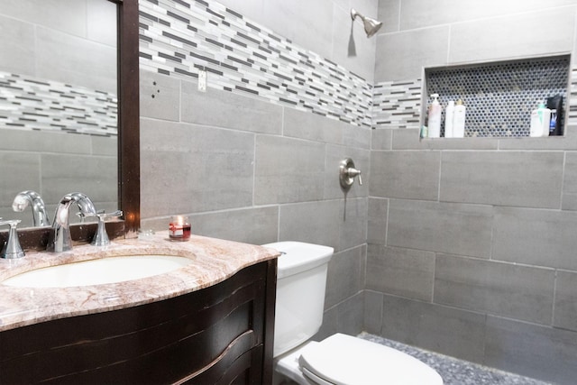 bathroom with vanity, toilet, and tile walls