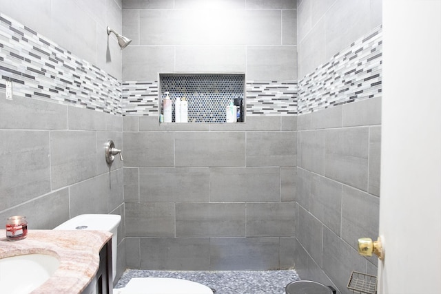 bathroom featuring a tile shower, vanity, and toilet