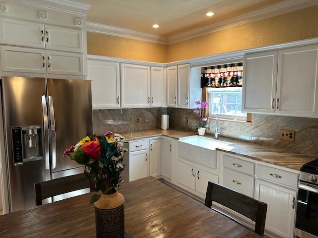 kitchen with appliances with stainless steel finishes, sink, white cabinets, and decorative backsplash