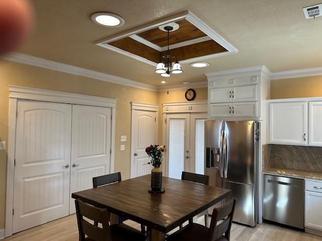 dining area featuring crown molding, light hardwood / wood-style flooring, an inviting chandelier, and a tray ceiling