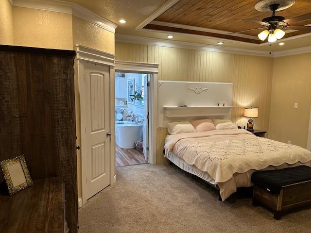 bedroom with connected bathroom, ornamental molding, a tray ceiling, carpet flooring, and ceiling fan