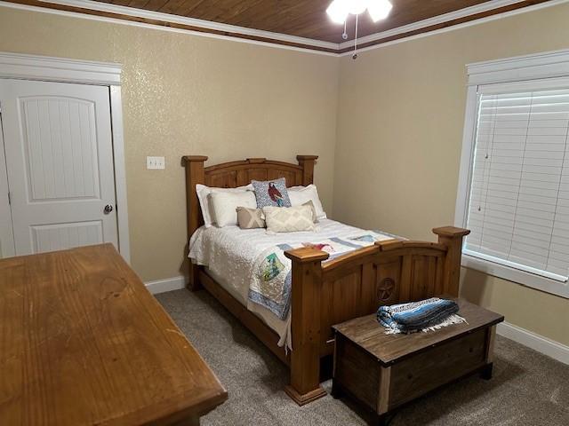 bedroom with dark carpet, ornamental molding, and wooden ceiling