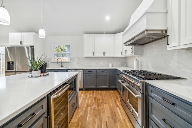 kitchen with premium range hood, appliances with stainless steel finishes, pendant lighting, beverage cooler, and white cabinets