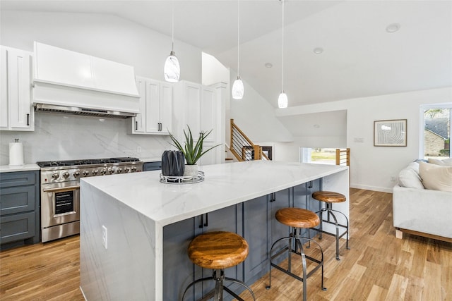 kitchen with light wood-type flooring, a kitchen island, open floor plan, stainless steel stove, and custom exhaust hood