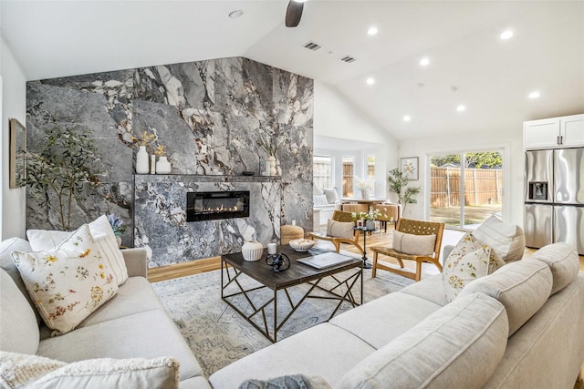 living room with a premium fireplace, vaulted ceiling, and light hardwood / wood-style flooring