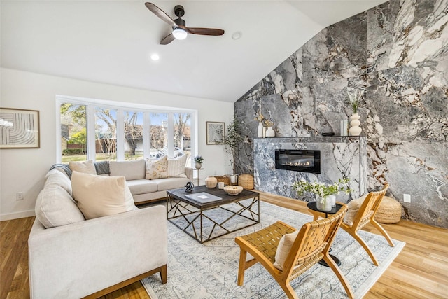 living room with ceiling fan, lofted ceiling, hardwood / wood-style floors, and a tile fireplace