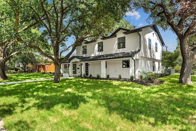 view of front facade featuring a front lawn, central air condition unit, and stucco siding