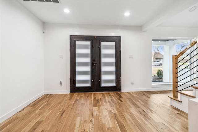 foyer with beam ceiling, light hardwood / wood-style flooring, and french doors