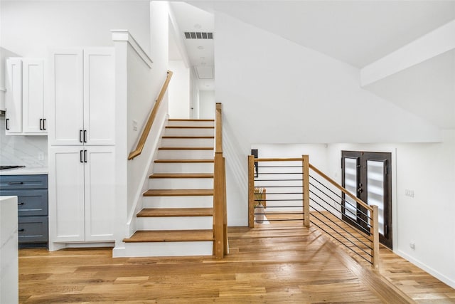 stairway featuring visible vents and wood finished floors