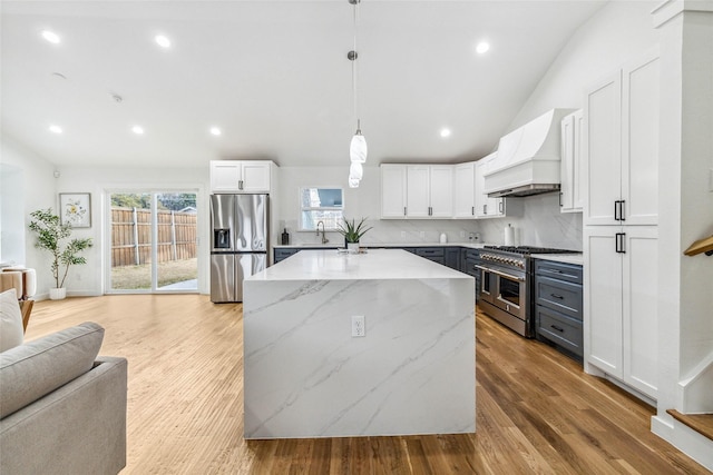 kitchen featuring pendant lighting, custom exhaust hood, stainless steel appliances, and white cabinets