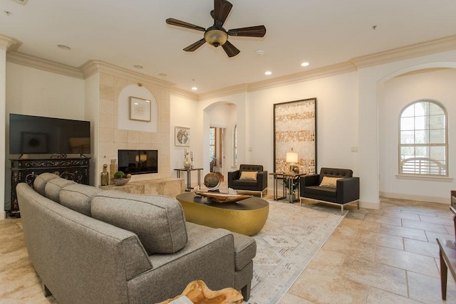 living room featuring crown molding, a tile fireplace, and ceiling fan