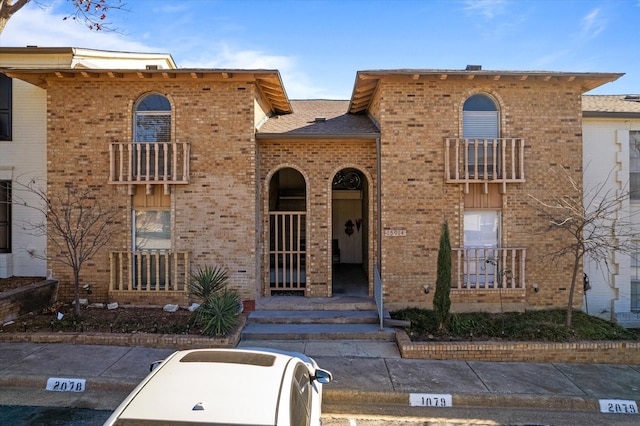 view of front of home with brick siding and a balcony