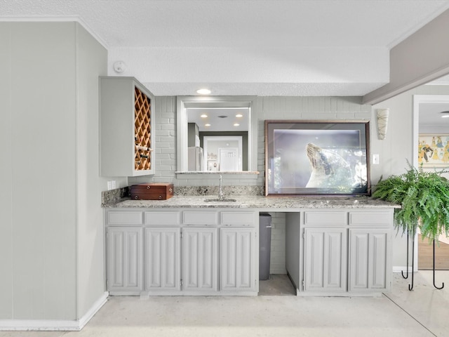 interior space with ornamental molding, sink, and light stone counters