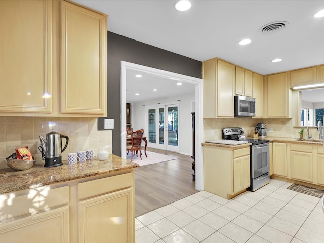 kitchen with sink, light brown cabinets, light tile patterned floors, appliances with stainless steel finishes, and backsplash