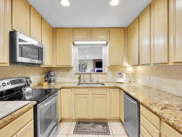 kitchen with light brown cabinetry, sink, light stone counters, light tile patterned floors, and appliances with stainless steel finishes