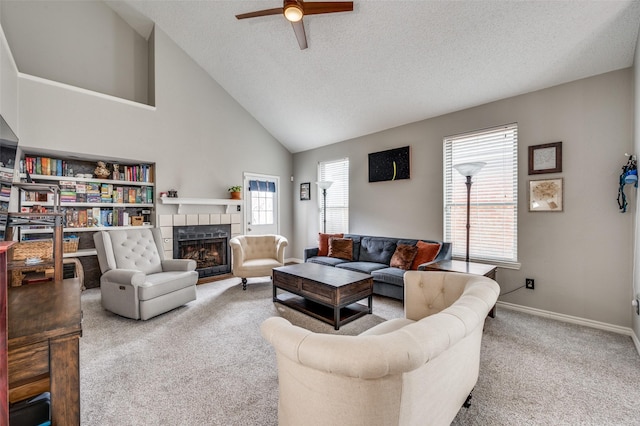 carpeted living room with ceiling fan, high vaulted ceiling, a tile fireplace, and a textured ceiling