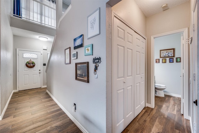 interior space with a textured ceiling, wood finished floors, and baseboards