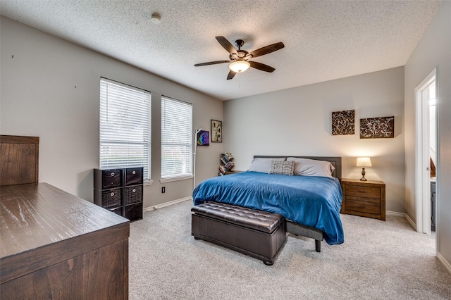 bedroom with ceiling fan, light colored carpet, and a textured ceiling