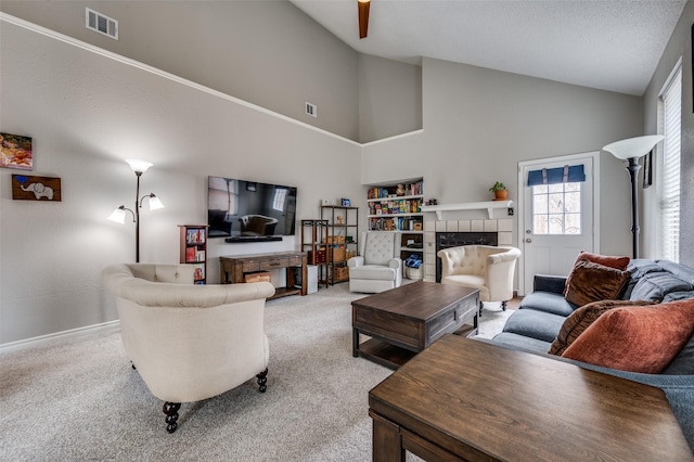 carpeted living room featuring a tiled fireplace and high vaulted ceiling