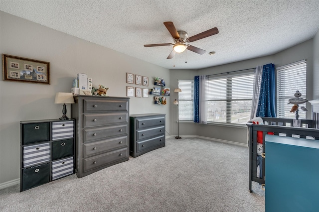 carpeted bedroom featuring a textured ceiling, ceiling fan, and baseboards