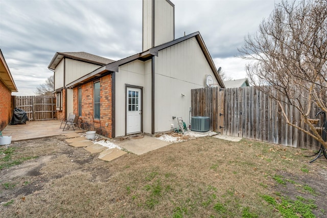 back of property featuring central AC unit, a lawn, a patio, fence, and brick siding