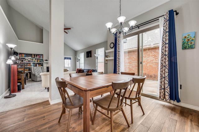 dining space featuring ceiling fan with notable chandelier, high vaulted ceiling, wood finished floors, and baseboards