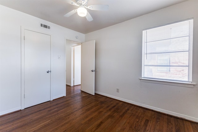 unfurnished bedroom with dark wood-type flooring, ceiling fan, and a closet