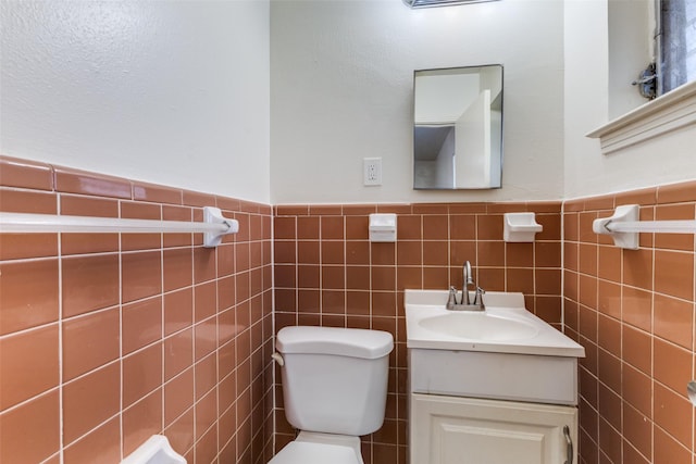 bathroom featuring vanity, tile walls, and toilet