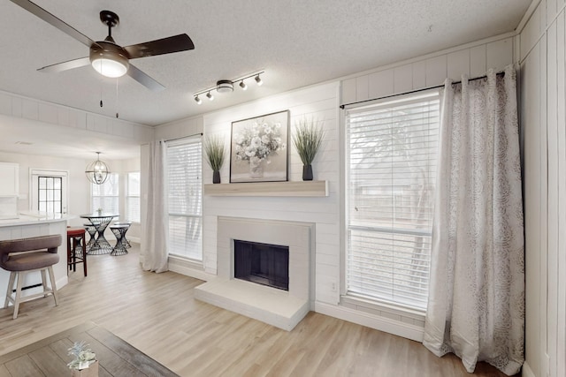 living room featuring a brick fireplace, a textured ceiling, and light hardwood / wood-style floors