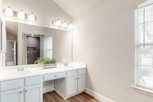 bathroom featuring lofted ceiling, wood-type flooring, a textured ceiling, and vanity