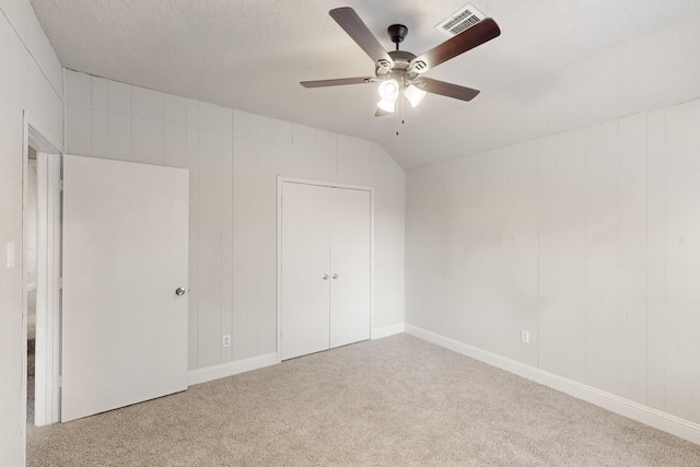 unfurnished bedroom featuring ceiling fan, lofted ceiling, and light carpet