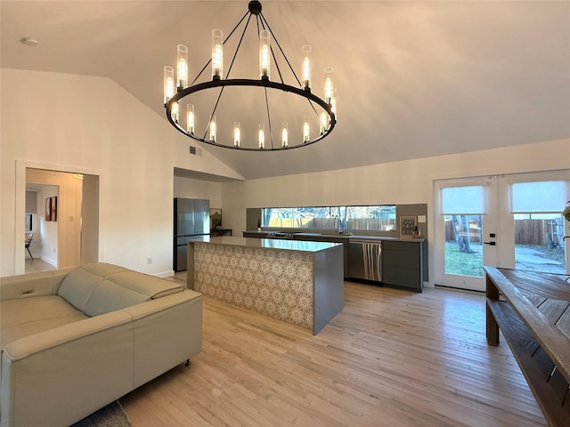 kitchen featuring black refrigerator, decorative light fixtures, dishwasher, lofted ceiling, and light hardwood / wood-style flooring